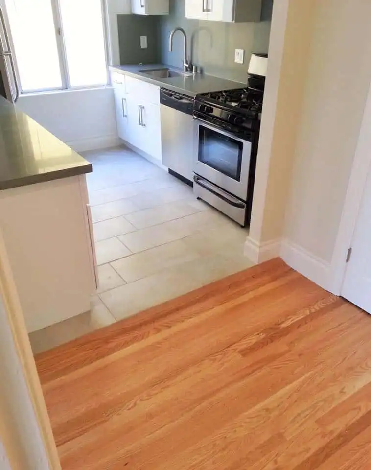 Wooden floor next to kitchen tiles